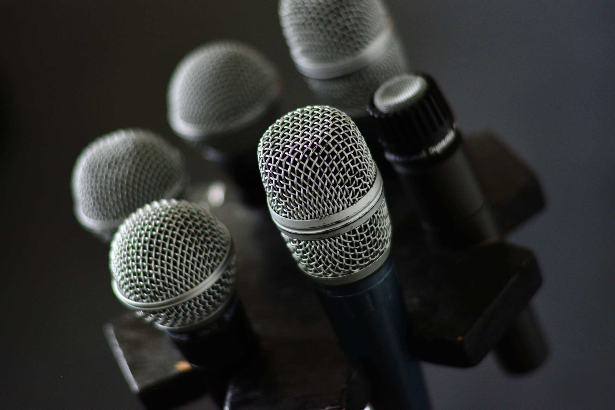A high-angle, close-up shot featuring a cluster of professional microphones on a stand, representing the focus, clarity, and audience-centric preparation required by the ABF Formula™ for effective professional speaking.